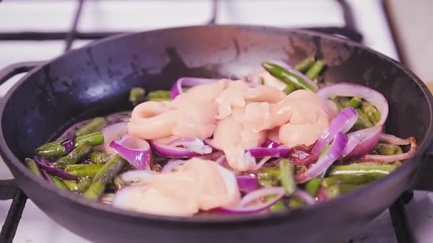 Una mano femminile aggiunge pollo a una padella con fagiolini fritti . — Video Stock