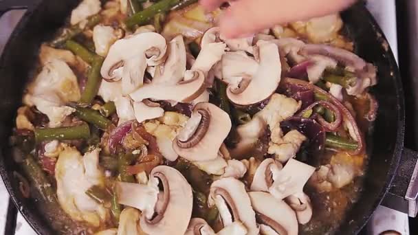 Samičí ruka přidá nakrájené houby do misky s kuřecím filé. — Stock video