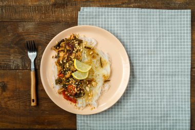 Peçetenin üzerinde funselli bir tabak var ve çam ağacının yanında sebzeli tavuk var..