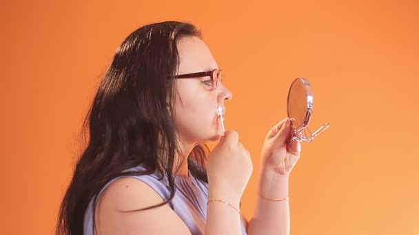 Μια νεαρή γυναίκα με γυαλιά μουτζουρώνει το πρόσωπό της με κρέμα.. — Αρχείο Βίντεο