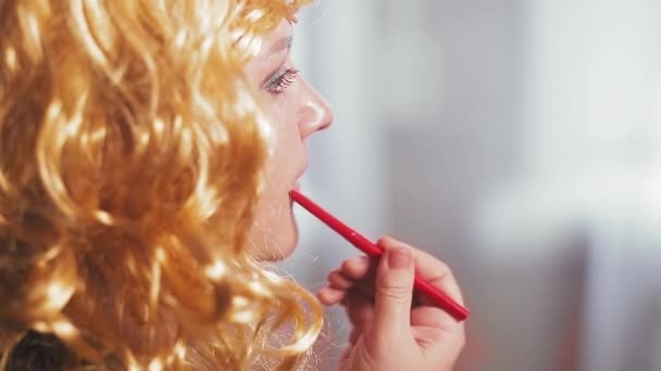 Una mujer en una peluca de carnaval está pintada con lápiz labial rojo . — Vídeos de Stock