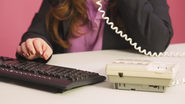 Mulher no escritório fala ao telefone está digitando no teclado . — Vídeo de Stock