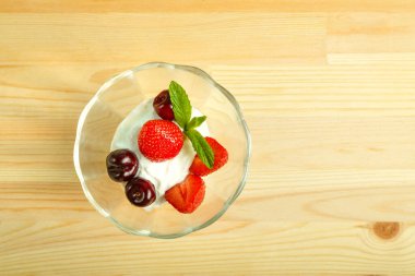 Tahta bir masada çilek ve kirazlı dondurma tatlısı. Boşluğu kopyala.