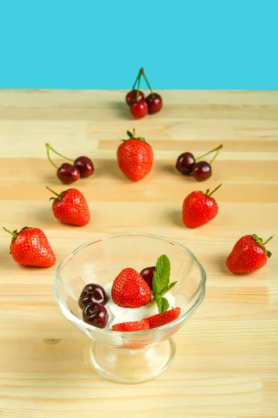 Dessert de crème glacée aux fraises et cerises dans une gourde sur une table en bois à côté de baies éparses . — Photo