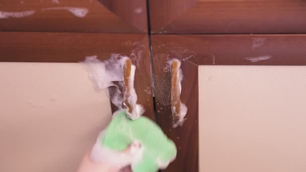 Ένα θηλυκό σφουγγάρια χέρι με ένα καθαριστικό πλένει τα έπιπλα της κουζίνας — Αρχείο Βίντεο