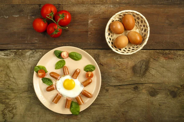 Ovos fritos com salsichas em forma de sol. Café da manhã infantil ao lado de ovos e tomates . — Fotografia de Stock