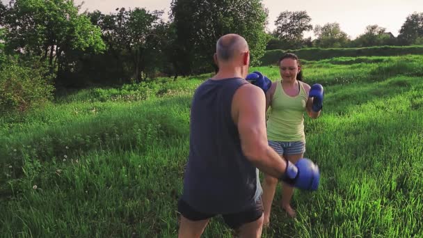 Homme et femme en été dans le parc s'entraînent à la boxe thaïlandaise avec des gants — Video