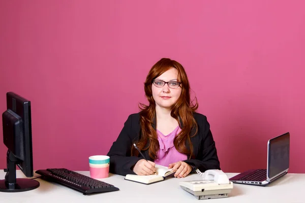 Jonge vrouw met bril in het kantoor aan tafel met een dagboek. — Stockfoto
