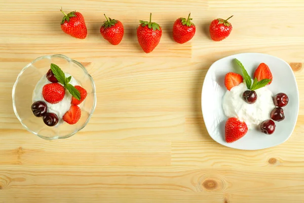 Postre de helado con fresas y cerezas en un plato sobre una mesa de madera y al lado de las bayas. Copiar espacio . — Foto de Stock