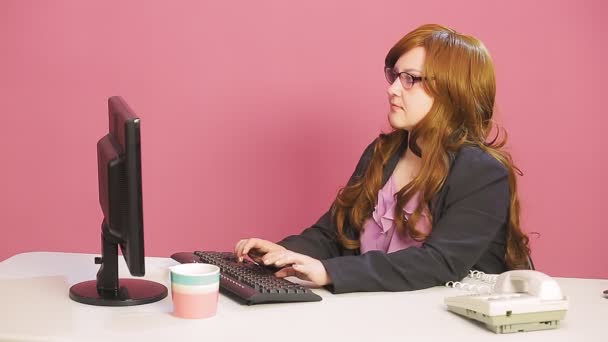Молодая женщина руководитель в офисе говорит по телефону и типы на компьютере — стоковое видео