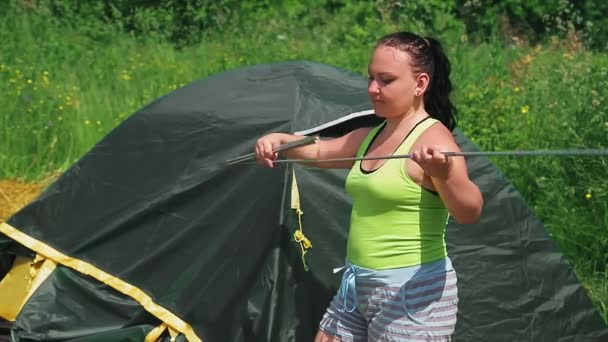 Uma mulher em uma clareira recolhe um monte de tenda — Vídeo de Stock