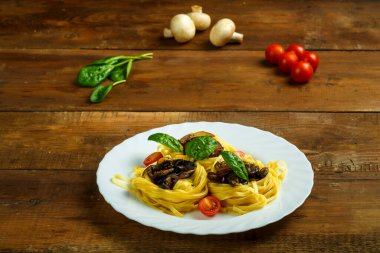 Peynirle doldurulmuş bir tabak makarna ve yakınlarda sebzeli mantar..