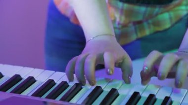 Kadın elleri bir sentezleyicide oynuyor.