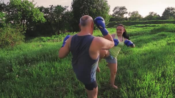 Muž a žena v létě ráno v parku trénují thajský box v rukavicích. — Stock video