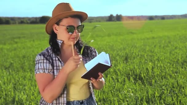 Agrónoma una mujer en un campo inspeccionar los cultivos a la luz y registra observaciones — Vídeo de stock