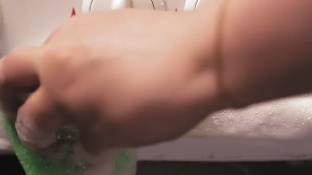 Mão feminina com uma esponja com um agente de limpeza limpa o painel com interruptores do fogão . — Vídeo de Stock