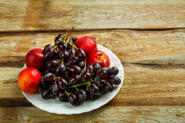Masadaki beyaz tabakta üzüm ve şeftali. Boşluğu kopyala.