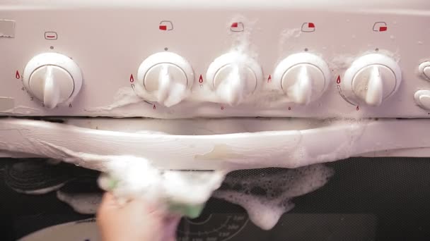 Mano femminile con una spugna con un detergente pulisce il pannello con interruttori della stufa. — Video Stock