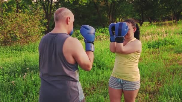 Hombre y mujer en la mañana en el parque están entrenando el boxeo tailandés en guantes . — Vídeo de stock