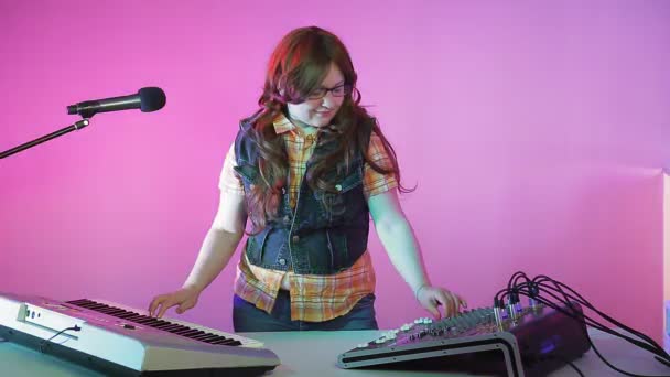 Una donna in uno studio di registrazione sintonizza un sintetizzatore e una console di missaggio. — Video Stock