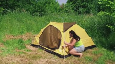 Bir adam ve bir kadın açık alana çadır kurup kemere çadır kurmuşlar.