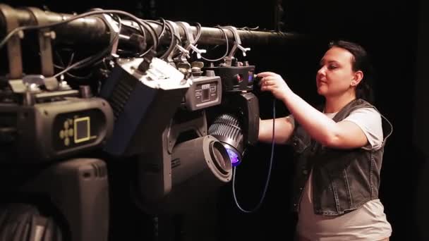 Egy női színpadi munkás csatlakoztatja a kábelt a világítóeszközökhöz. — Stock videók