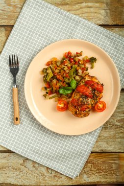 Mendilinde çatal olan bir tabakta sebzeli domatesli fırında tavuk göğsü..