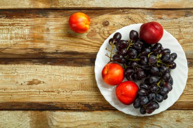 Masadaki beyaz tabakta üzüm ve şeftali. Boşluğu kopyala.