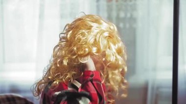 Aynanın önünde duran bir adam altın bukleli bir palyaço peruğu takıyor..