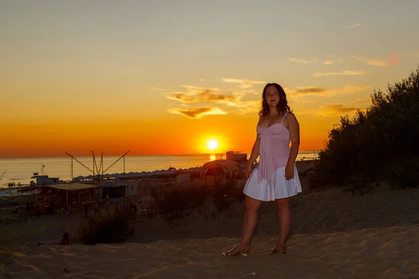 Femme en robe blanche sur fond de mer au coucher du soleil. — Photo