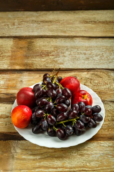 Виноград и персики на белой тарелке на столе. Копирование пространства . — стоковое фото