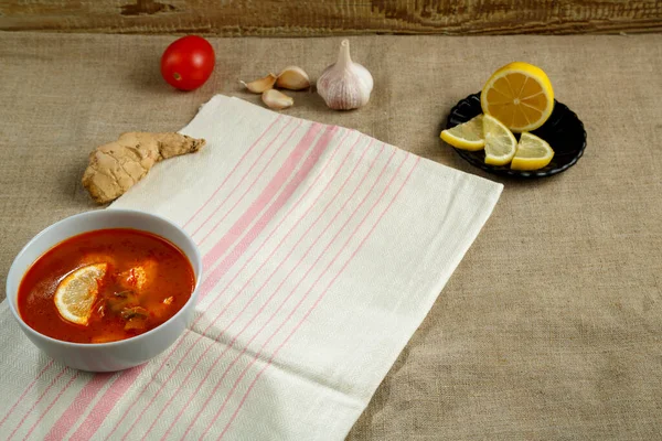 가까운 곳에 있는 아마포 식탁보와 아마포 냅킨, 마늘, 레몬에아이 톰 얌 수프를 얹어 놓는다. — 스톡 사진
