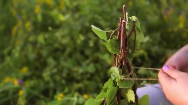 Dişi eller huş dallarını ince bir iple bağlar.