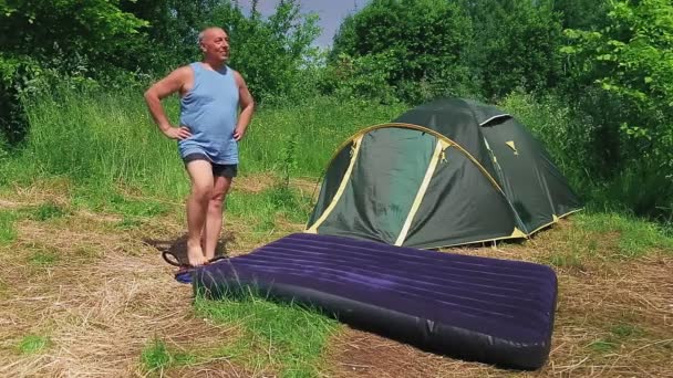 Un homme pompe un matelas pneumatique à l'aide d'une pompe — Video