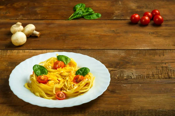 Plate on the table pasta nests stuffed with cheese and cherry tomatoes with herbs.