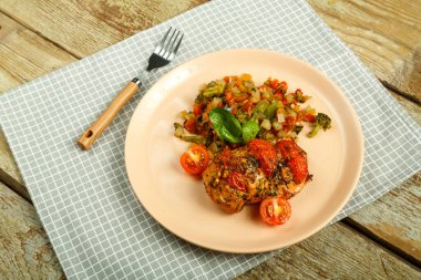 Fırınlanmış tavuk göğsü, domates ve sebzelerle süslenmiş, çatallı bir tabakta, peçeteyle..