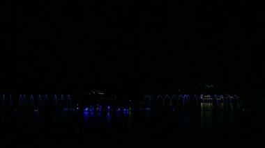 Farklı renklerde parlayan alışılmadık su bileşimleri gece gökyüzüne karşı çeşmeleri gösterir.