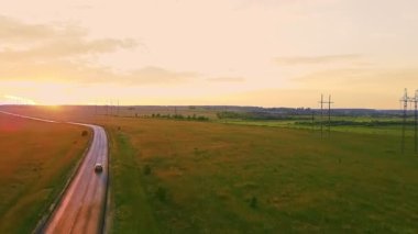 Kırsal alanda yol gün batımında bir tarlanın ortasında ve yüksek voltajlı hatlarda..