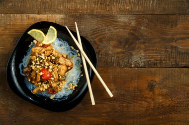 Funselli Nastol siyah tabak ve çubukların yanında Tayland soslu sebzeli tavuk..