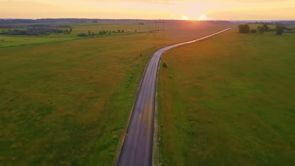 En kvällsväg på landet mitt på ett fält vid solnedgången och högspänningsledningar. — Stockvideo
