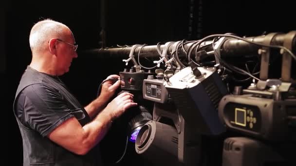 Een man zet het licht op een concertpodium. — Stockvideo