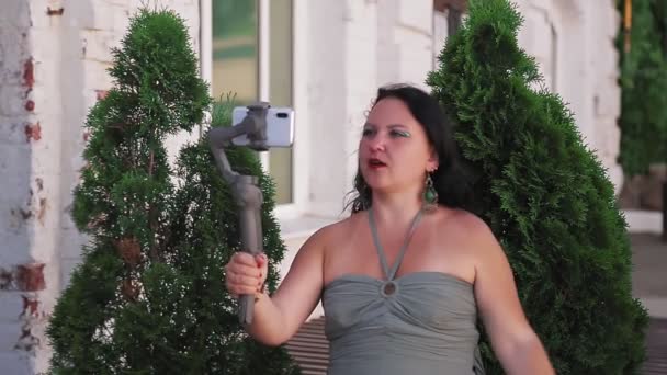 Una blogger donna con un cellulare parla di viaggi parla di una vecchia casa. — Video Stock