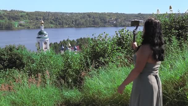 Een vrouwelijke blogger zendt uit vanaf een bergtop met uitzicht op de rivier. — Stockvideo