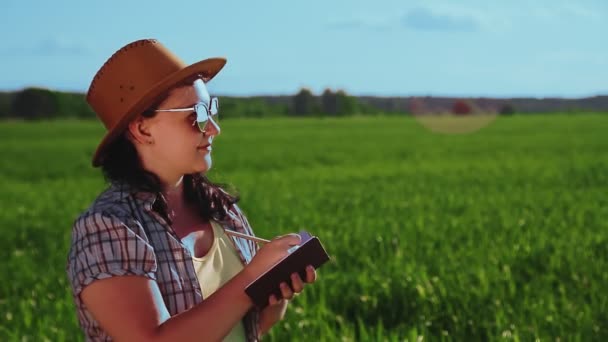 Agronom eine Frau auf einem Feld inspiziert Pflanzen und protokolliert einen Bericht. — Stockvideo