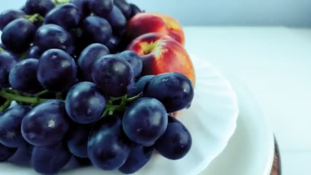 El plato con las uvas y los melocotones gira en el círculo sobre el fondo blanco . — Vídeos de Stock