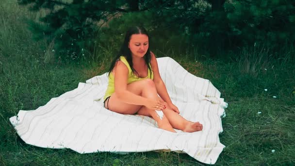 Una donna in una radura si rade le gambe su un foglio. — Video Stock