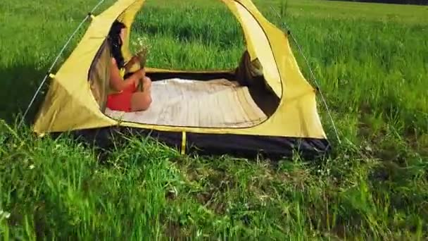 Femme dans une tente dans une clairière par une journée ensoleillée. Le passage de la caméra à travers la tente. Caméra mobile — Video