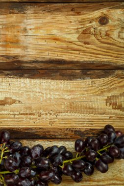 Tahta bir masada bir demet koyu üzüm. Kpi yeri.