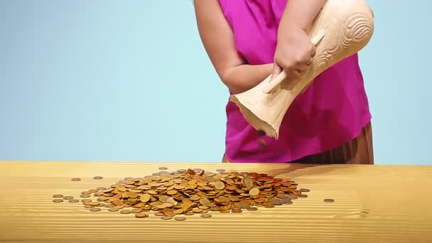 The woman pours coins from a large jug onto the table — Stock Video