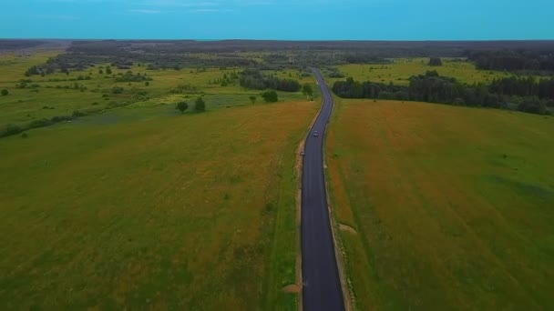 Дорога почти без автомобилей в сельской местности в середине поля на закате и высоковольтных линий — стоковое видео